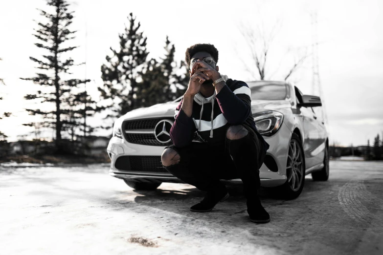 a person sitting down in front of a car on a phone