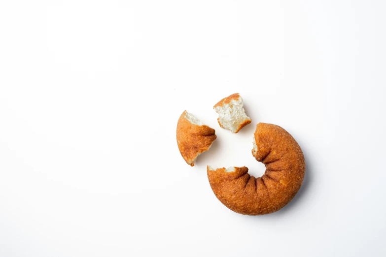 a piece of bread and two pieces of powdered dough are on a white surface