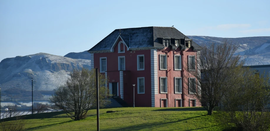 large pink building in green field next to mountains