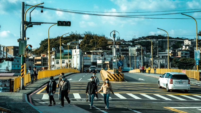 people walking across an urban street, in the daytime