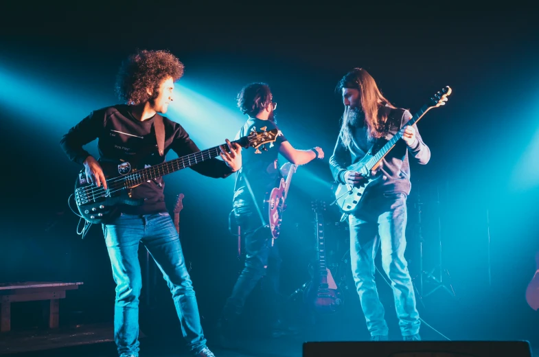 three people are playing the guitar on stage