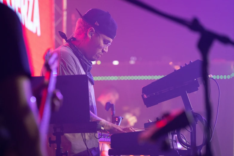 a dj plays on the keyboards as the crowd watches