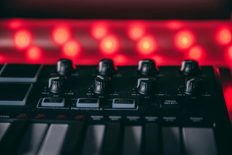 closeup of an electronic synthesizer with a red lighting behind it