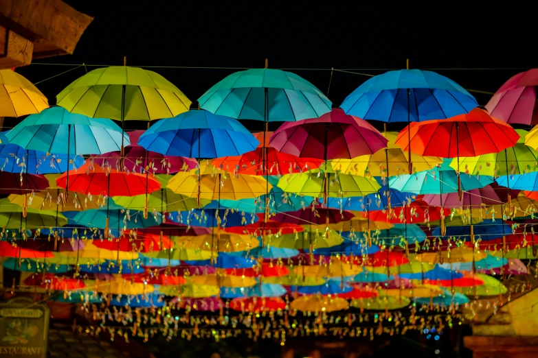 many umbrellas hanging from the ceiling at night