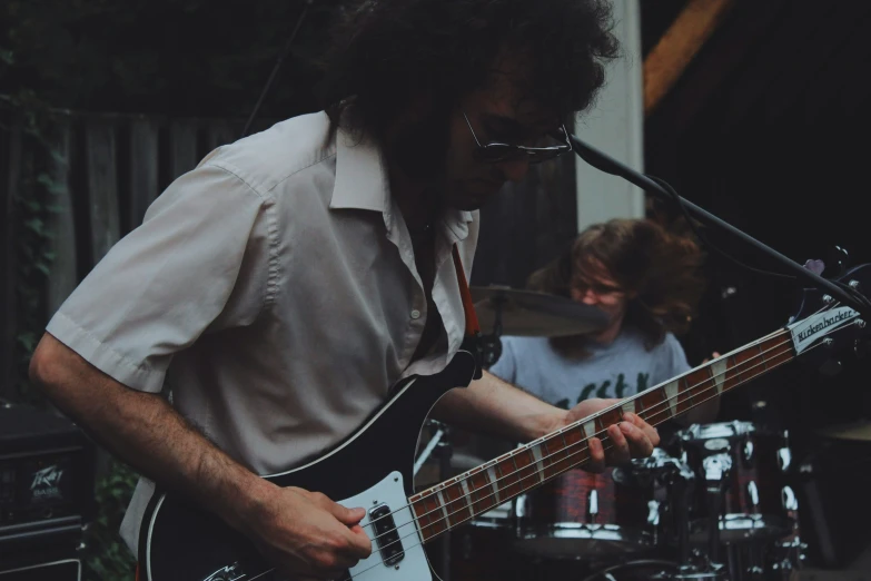 man playing guitar while another plays the drums in front