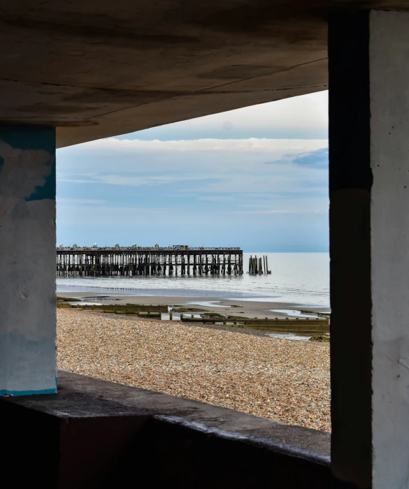 an open door overlooks the beach as a view of a pier sits in the distance