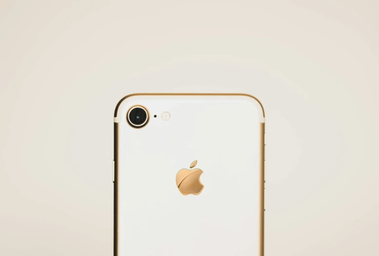 an iphone with a golden camera sits on a stand