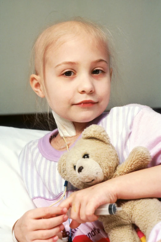 a child holds a teddy bear in the hospital