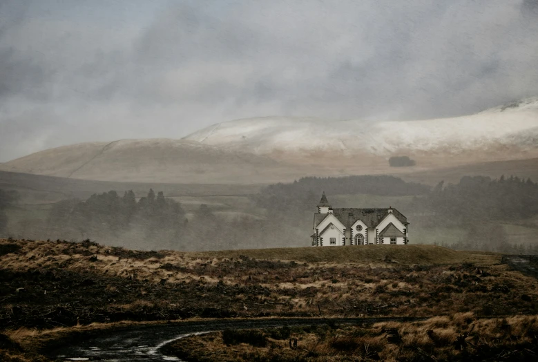 a house on top of a grassy hill with fog in the sky