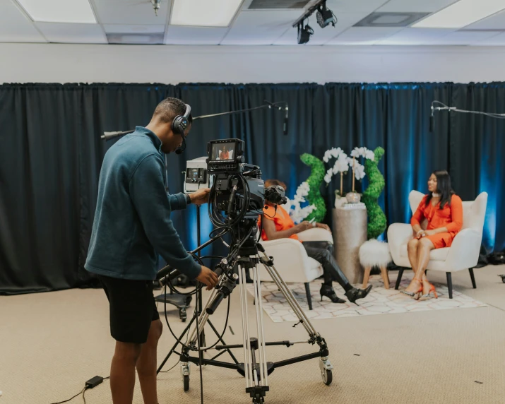 the man is filming a women sitting in chairs