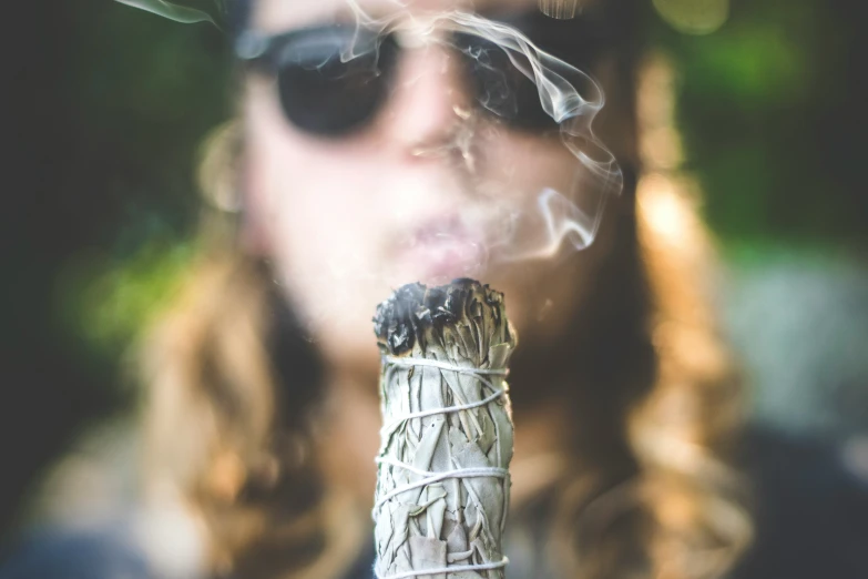 someone smokes out while holding a smoke stick