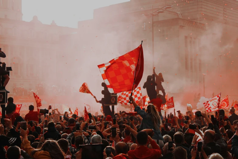 a large crowd stands behind red flags in front of building