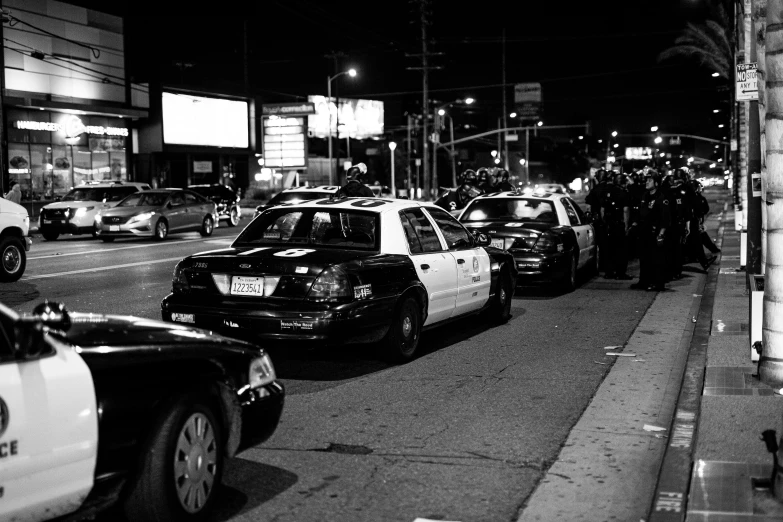 police standing on a sidewalk while several cops are outside the building