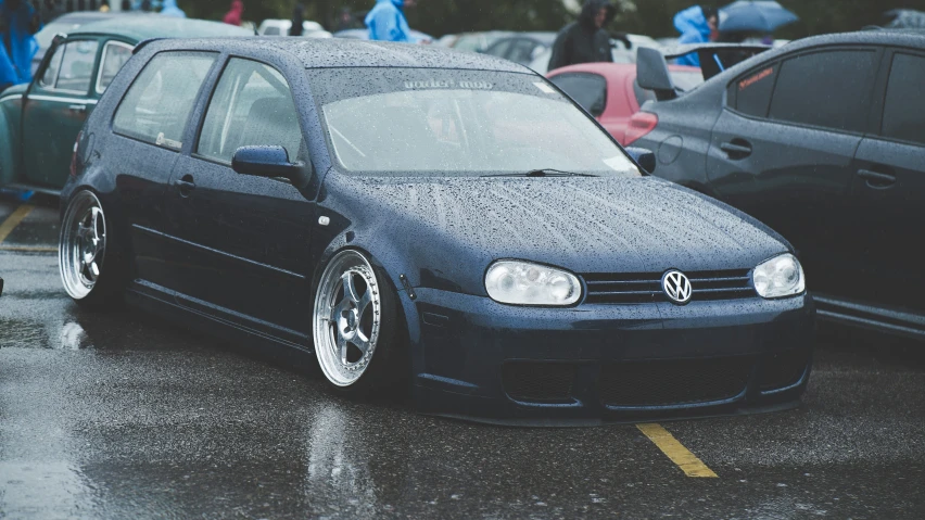 two cars are parked together in a lot covered by the rain