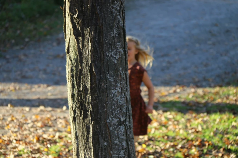 the little girl is standing next to the tree