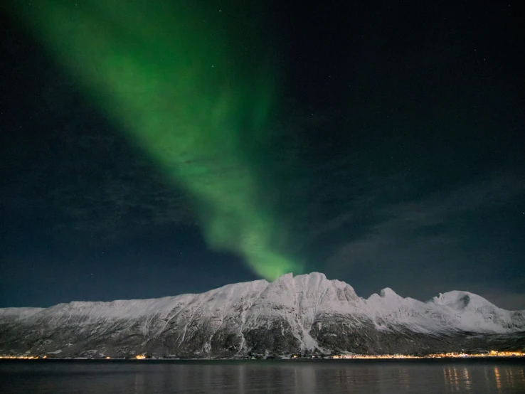 an aurora bore on top of the mountains with snow and lights on