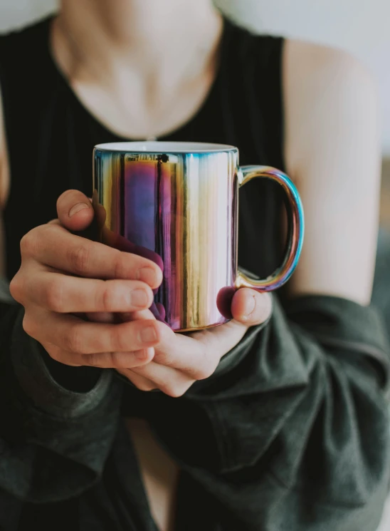 a woman is holding a coffee mug with color strips