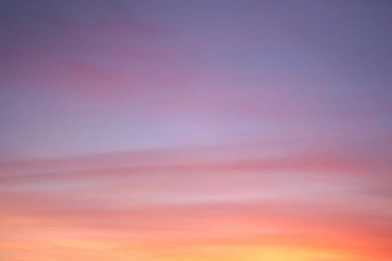 the airplane is flying against a colorful sky