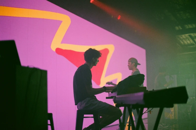 people sit at small tables on stage using keyboards