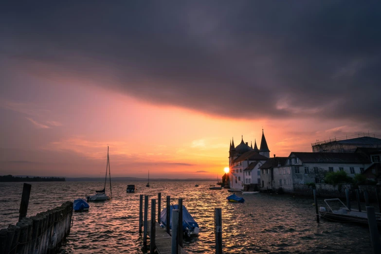 the sun is setting on the water in a town