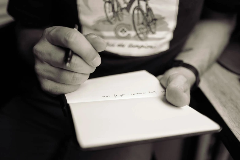 a person sitting down writing on a note pad