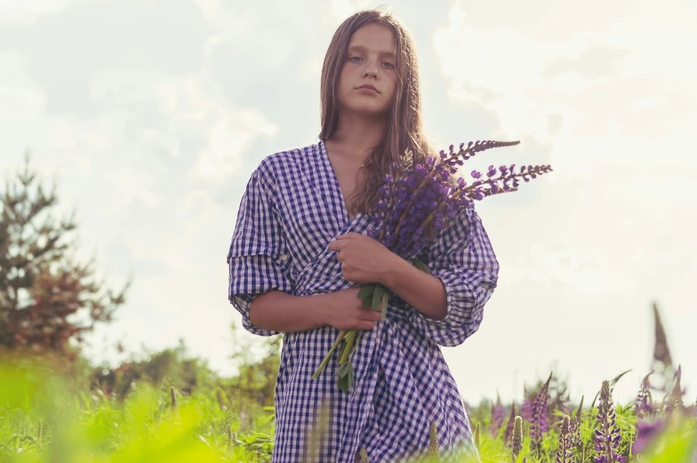 a woman is standing with her arms crossed in a field of purple flowers