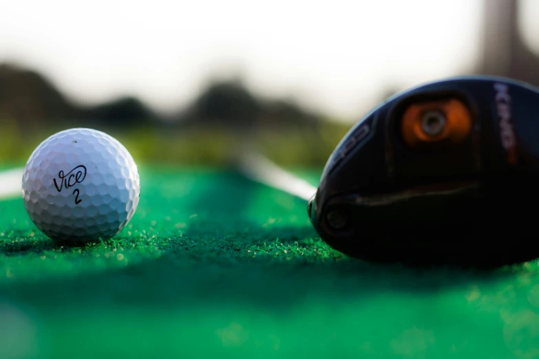 a golf ball with the word golf written on it next to a black golf club