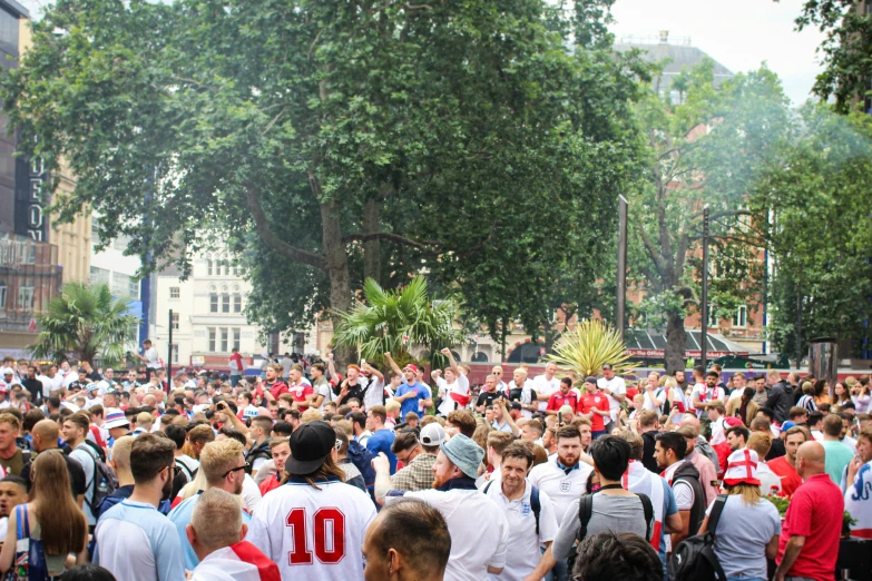 large group of people walking on sidewalk next to trees