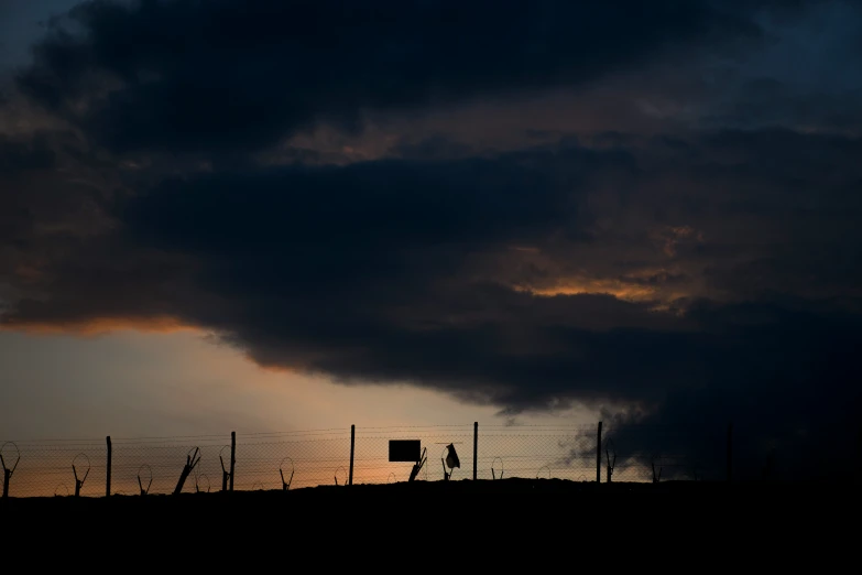 a tall building sitting in the middle of a field under a dark sky