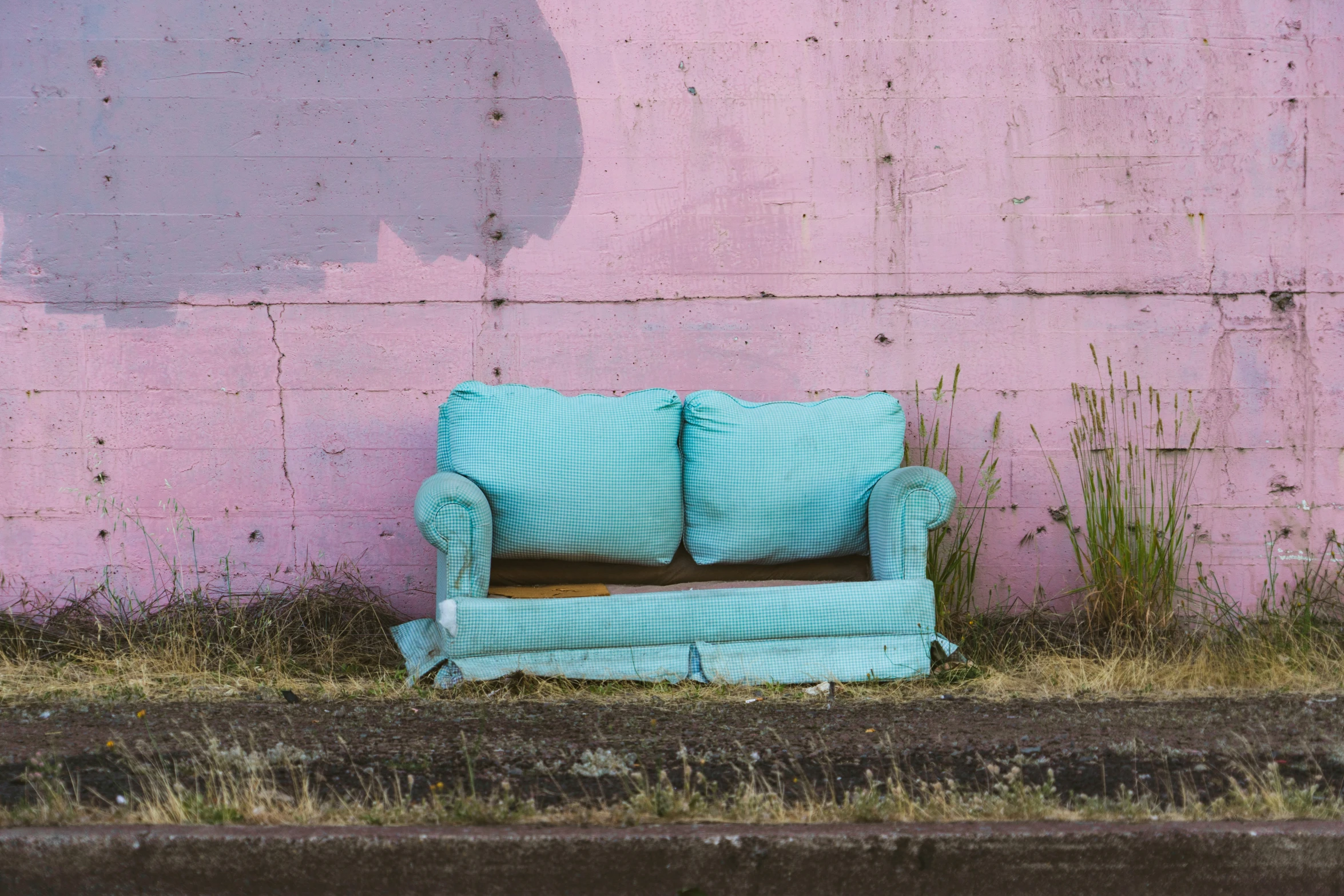 an old couch in front of a pink painted wall