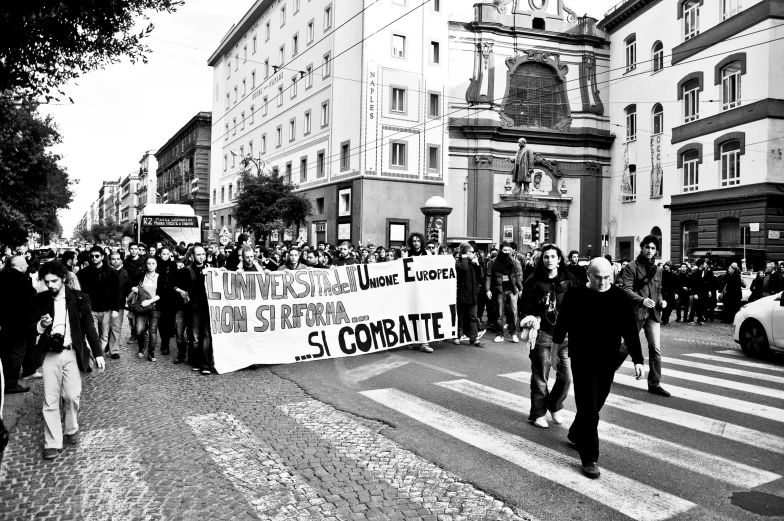 a protest with people marching in the street in front of two buildings