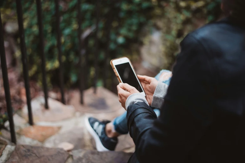 someone sitting on steps while holding a smart phone