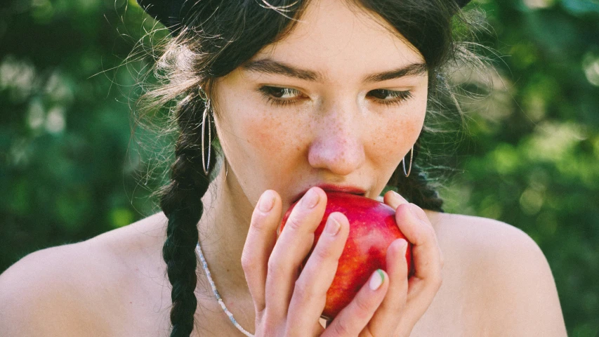 a shirtless woman biting into an apple while wearing a costume