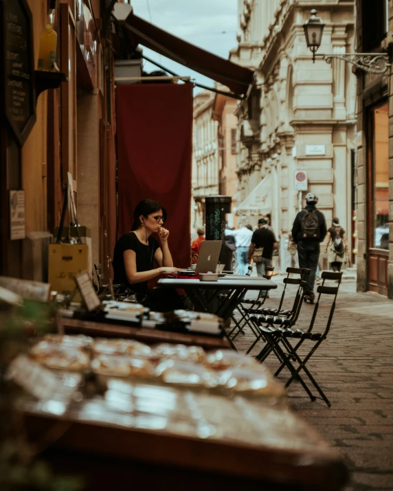 a woman sitting on a bench using her laptop computer