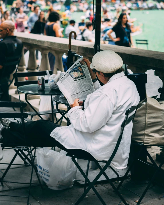 a man sitting in a chair reading a newspaper