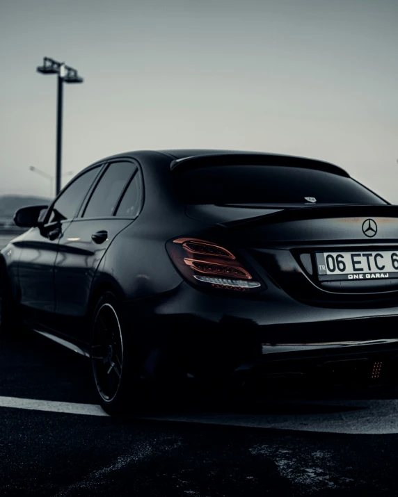 this black mercedes benz is driving through an empty parking lot