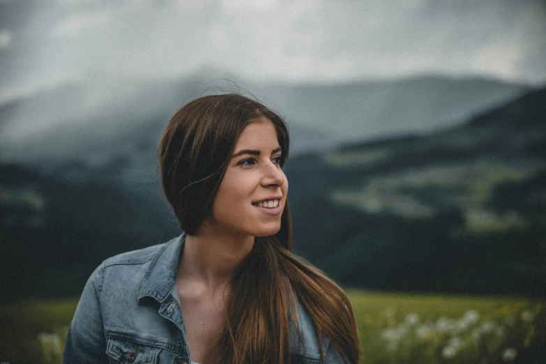 a woman wearing a jean jacket is smiling