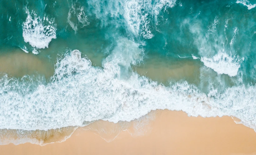 top view of a beach showing sand, ocean and waves