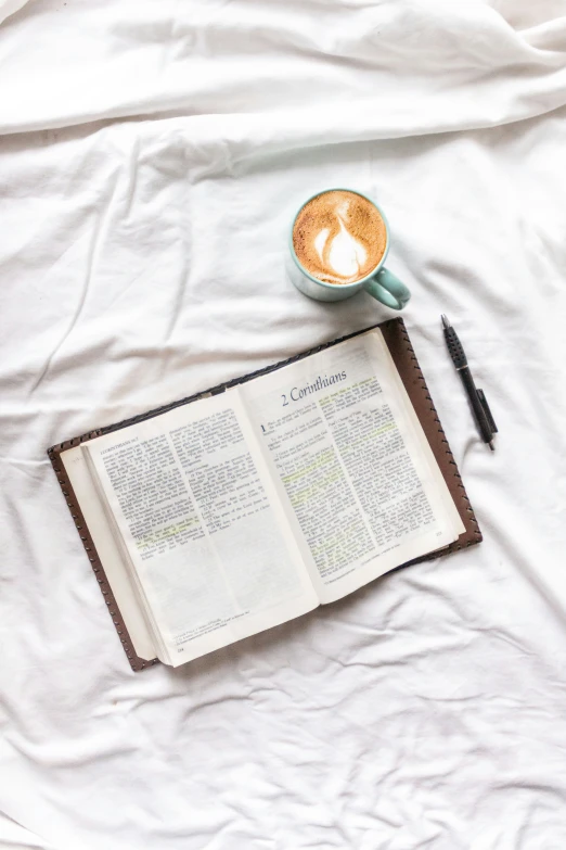 a book and pen are shown on top of a white sheet