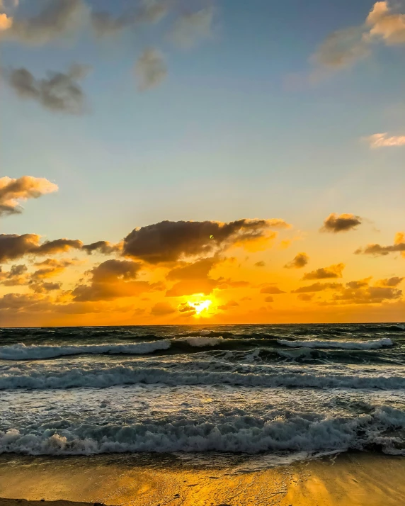 a view of an ocean sunset with clouds and sun setting over the water