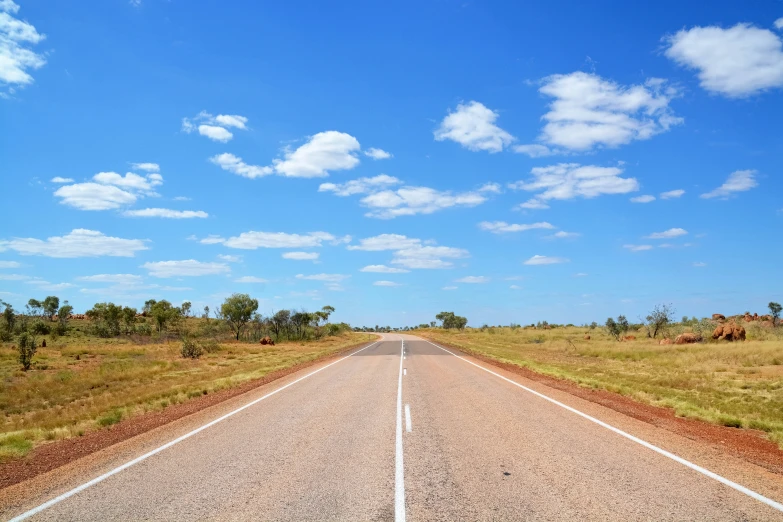 a straight road stretches across grassy land to the horizon