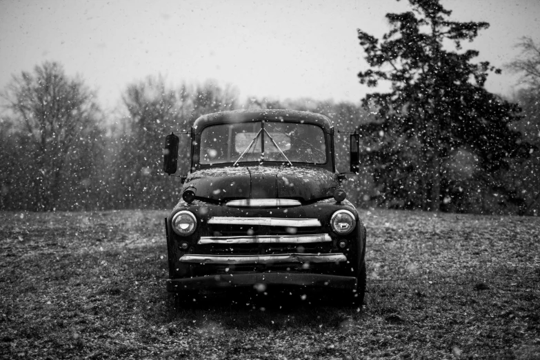an old truck sitting in a field covered in snow