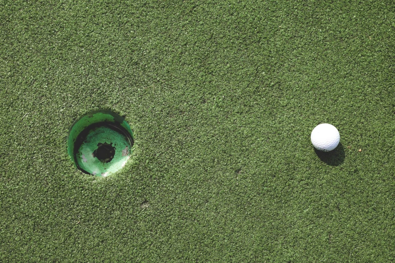 an image of two balls on grass with hole on the other side