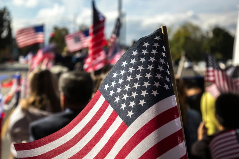 an american flag is held in the wind at a gathering