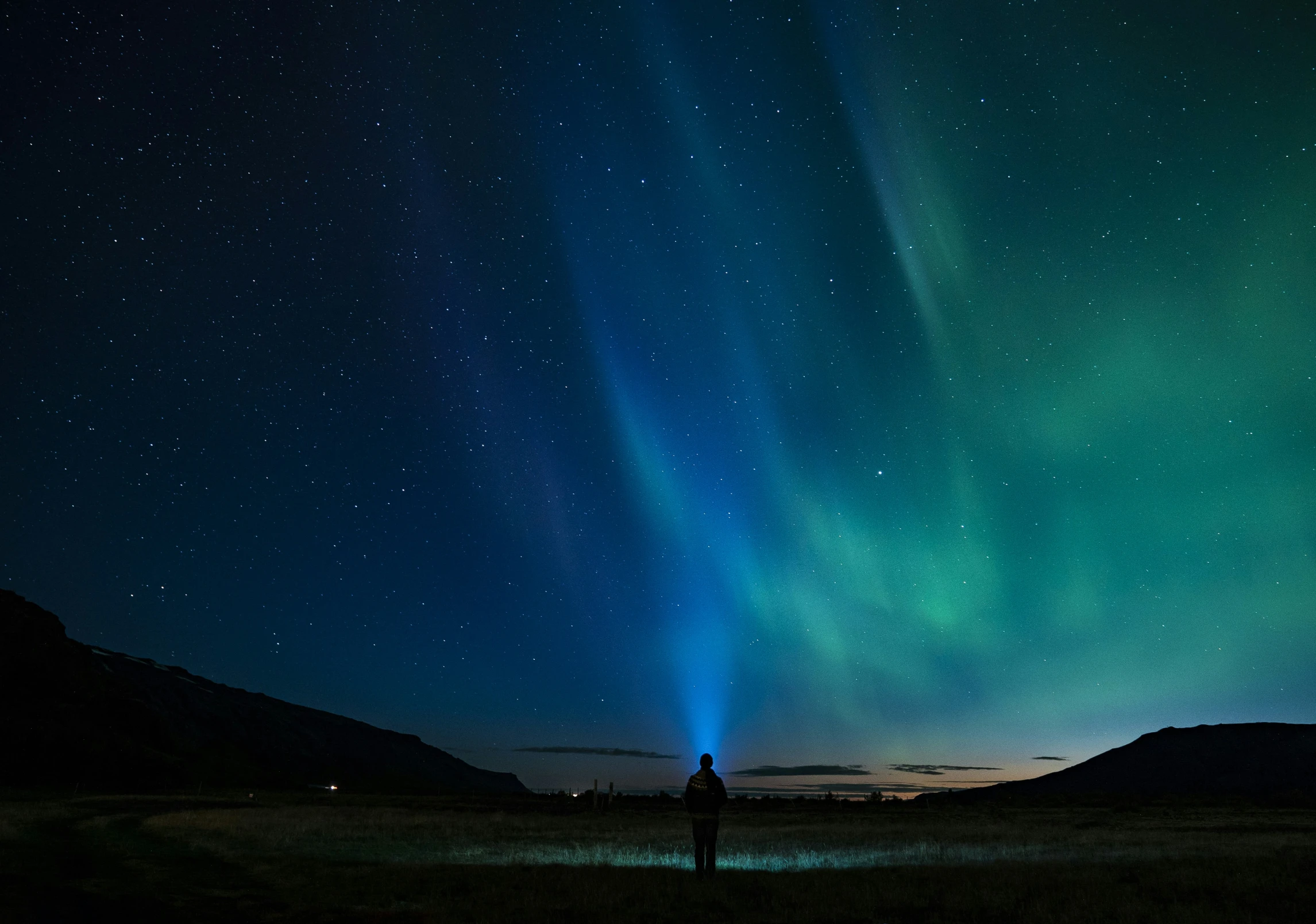 a man is standing under a large aurora aurora in the sky