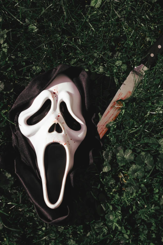 a scary mask and knife lying on the grass