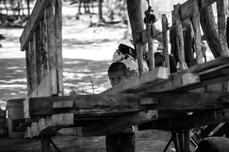 a black and white po of a boy looking over a wood beam