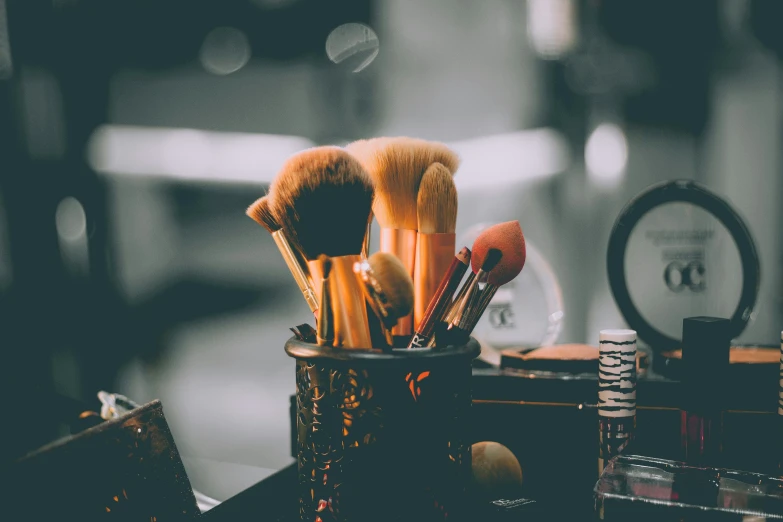 a metal cup with brushes and makeup creams in it