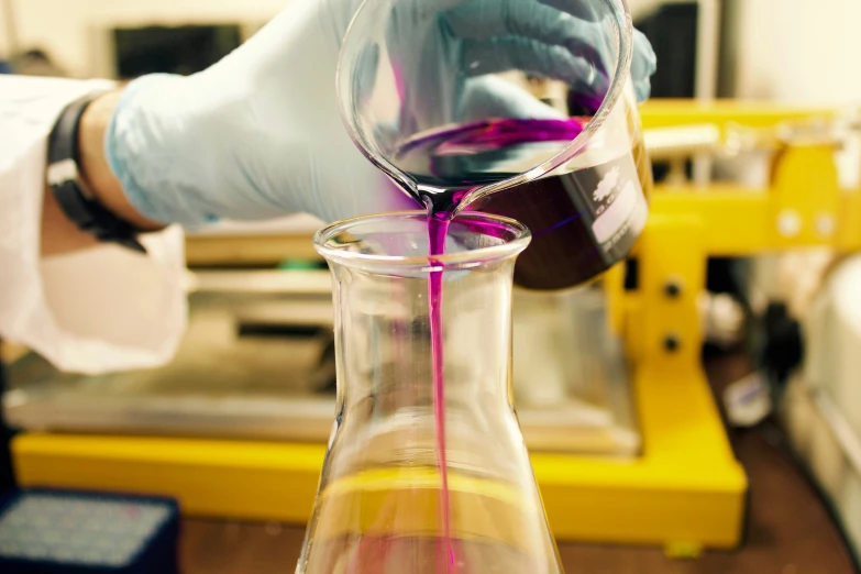 a person's hand pouring liquid into a flask