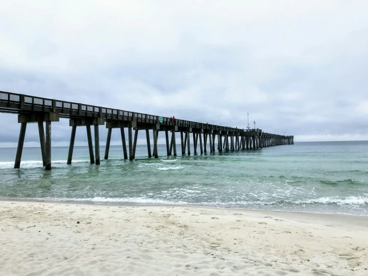 a wooden pier in the ocean on a beach